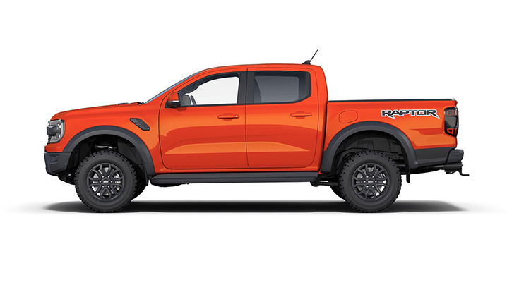 Seitenansicht eines leuchtend orangefarbenen Ford Ranger Raptor mit großen Reifen.